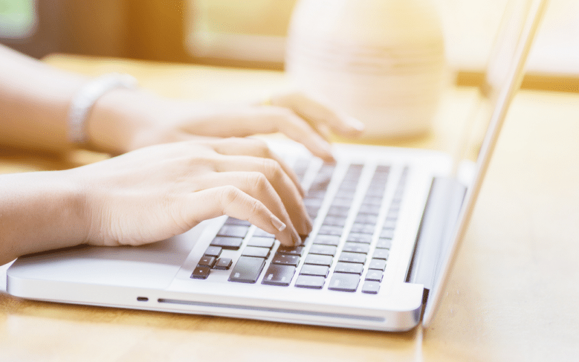 Et bilde av et par hender som skriver på en laptop