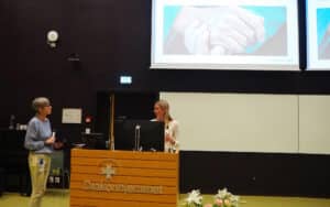 Foreleser og ordstyrer i dialog foran deltakerne.