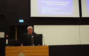 Et bilde av Tore Kvien på talerstolen. Man ser første bildet av presentasjonen bak han med tittel på foredraget.